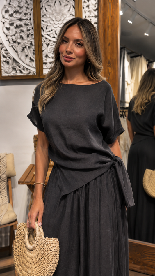Close-up front view of a charcoal maxi dress with round neckline and side tie waist detail