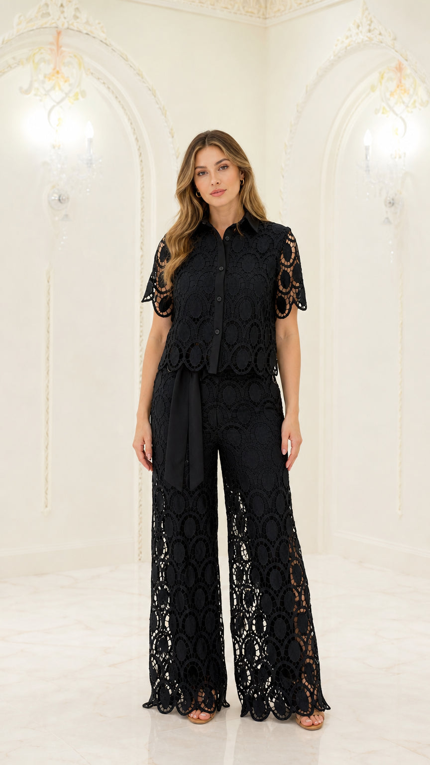 Front full-length view of woman wearing black geometric lace short sleeve shirt and matching wide-leg trousers