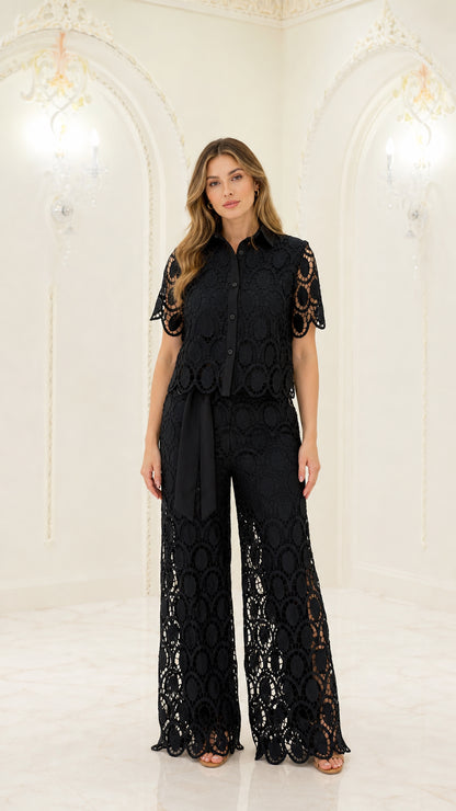 Front full-length view of woman wearing black geometric lace short sleeve shirt and matching wide-leg trousers