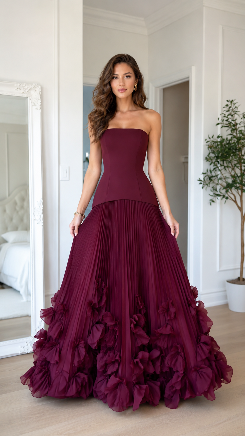 Front view of burgundy strapless pleated maxi gown with dramatic floral ruffle hem