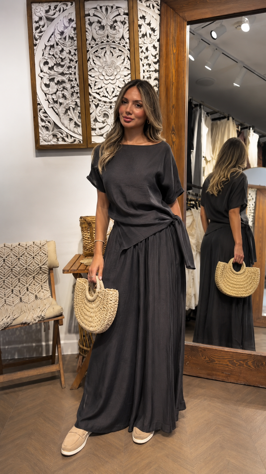 Woman wearing a charcoal draped waist short sleeve maxi dress with a flowing skirt, front view