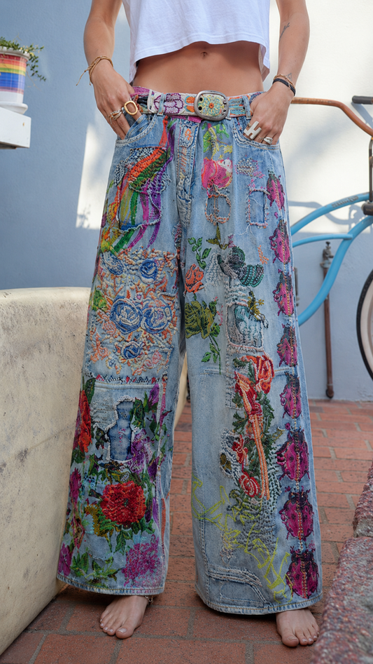 Front view of light blue wide leg jeans with colorful floral patchwork and statement belt