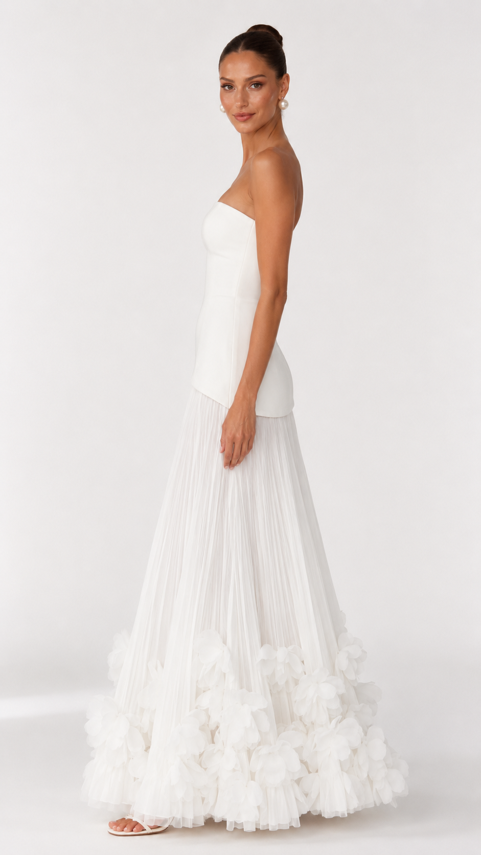 Side view of ivory strapless maxi dress with fitted bodice and full pleated skirt