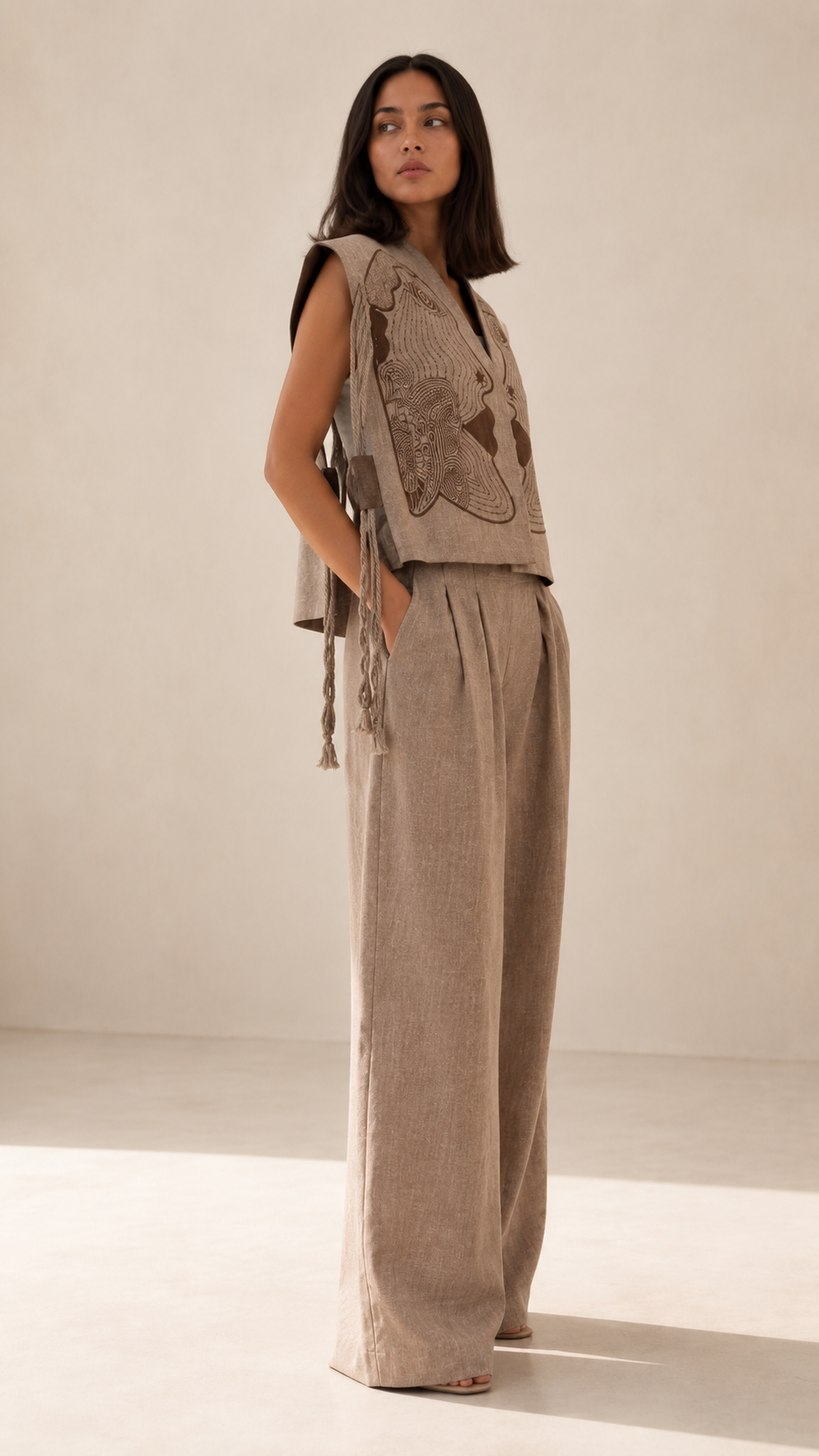 Side view of taupe sleeveless embroidered vest with matching wide leg trousers