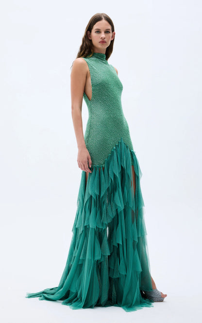 Side view of emerald fitted high-neck evening gown with dramatic sheer ruffle skirt
