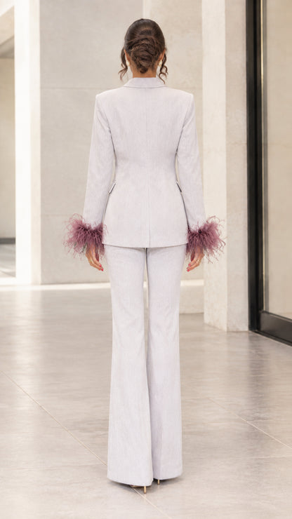 Back view of woman showing tailored silhouette of light grey blazer and flare pants