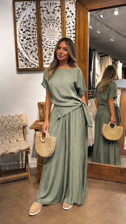 Woman wearing a sage green draped waist maxi dress with short sleeves and full-length skirt