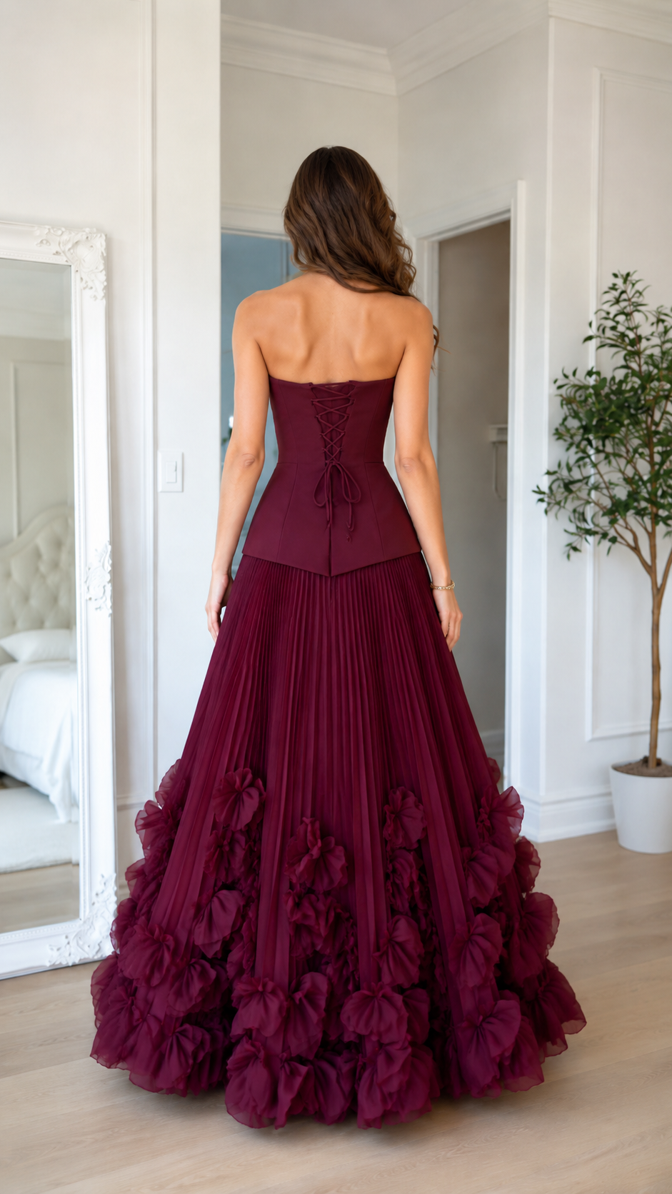 Back view of burgundy strapless gown with lace-up back and voluminous ruffle hem