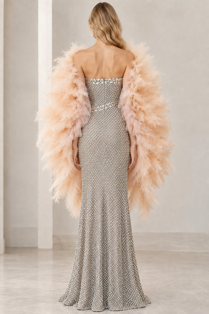 Back view of model showcasing the sleek back fit of the silver strapless evening gown with feather shawl