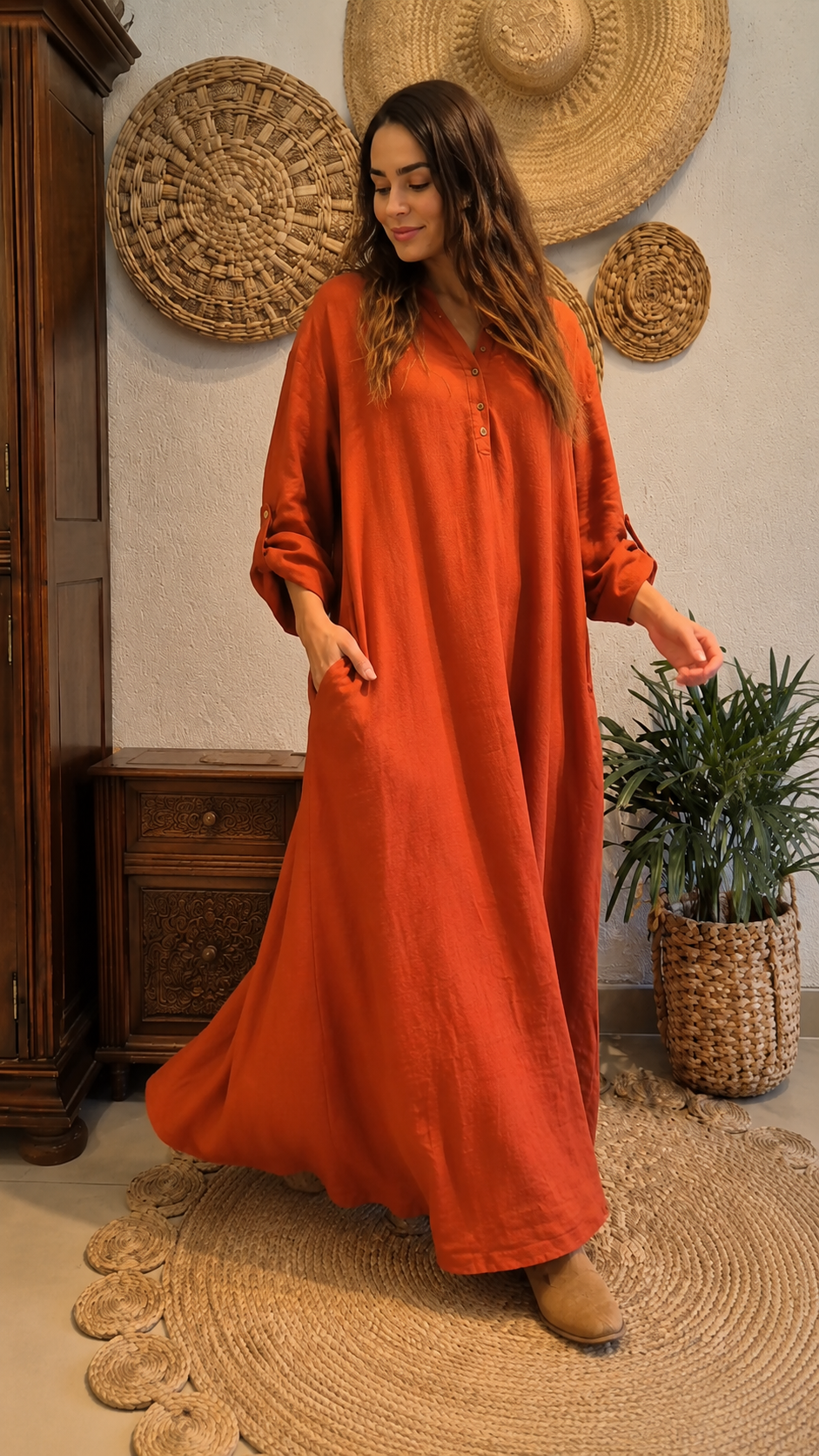 Angled view of rust flowing maxi dress showing movement and rolled sleeves