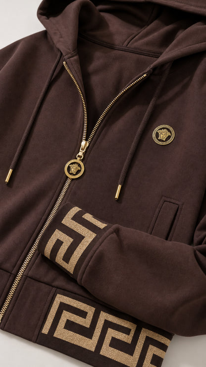 Close-up detail of the gold zipper, medallion pull, and geometric trim on the Brown jacket