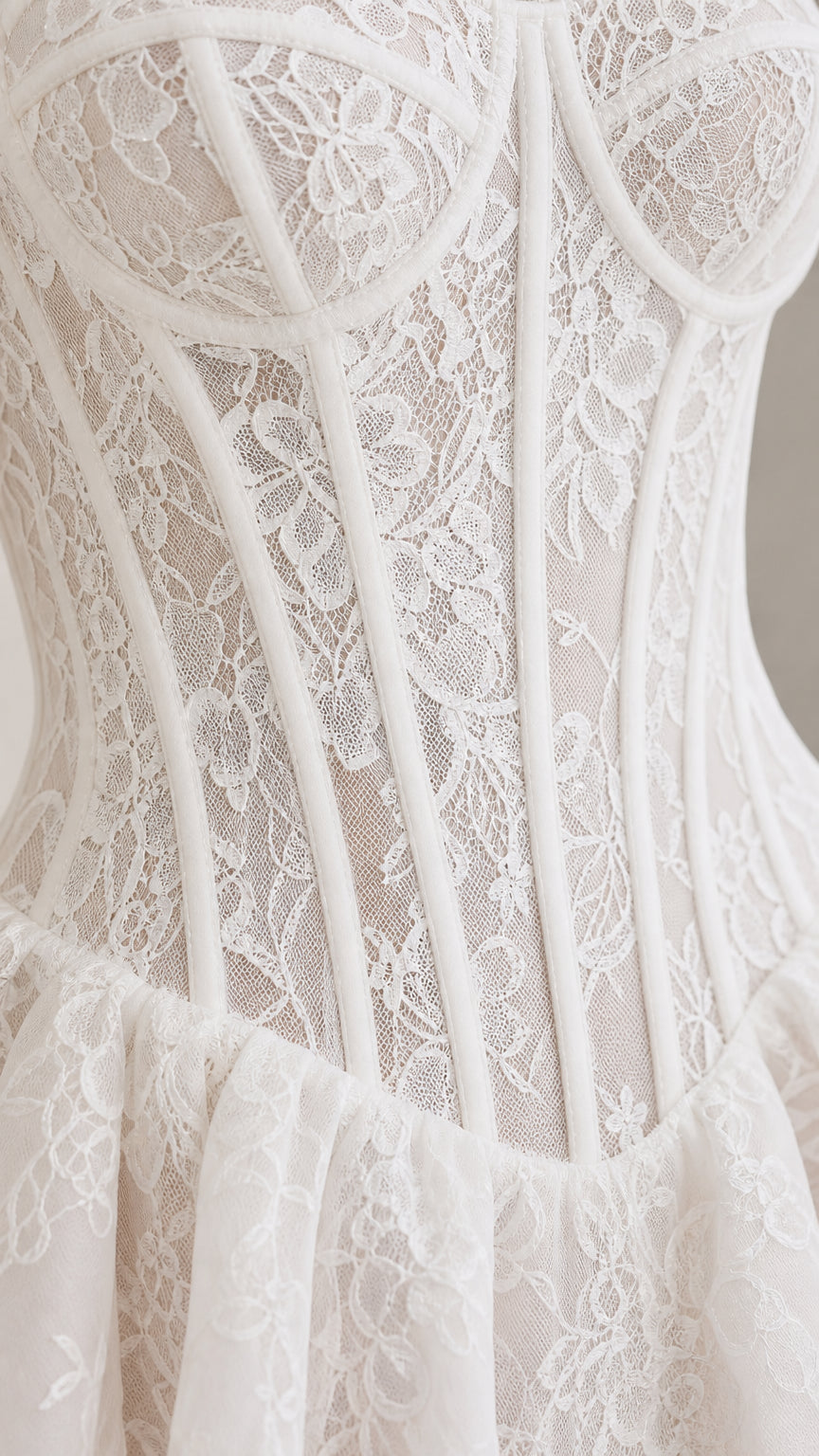 Close-up detail of white floral lace texture, cups, and corset boning