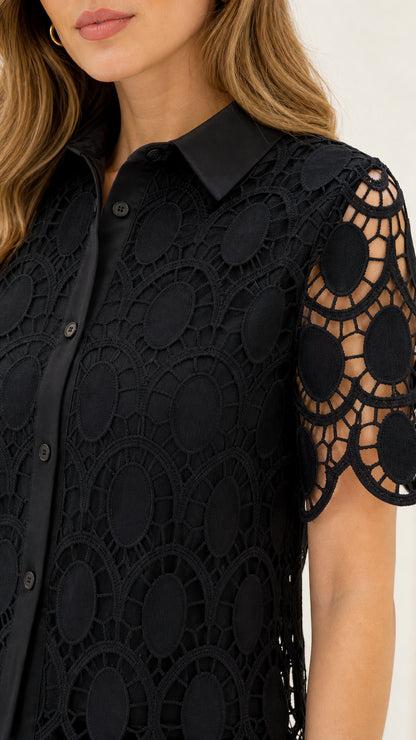 Close-up detail of black geometric lace collar, button placket, and openwork short sleeves