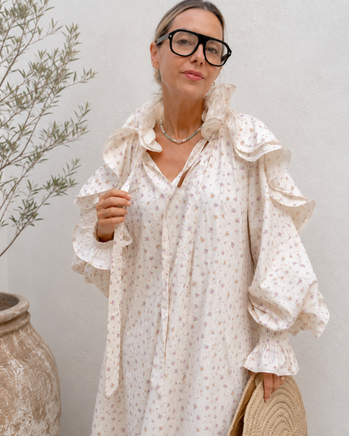 Close-up of ruffle collar tie neckline and floral print on cream midi dress