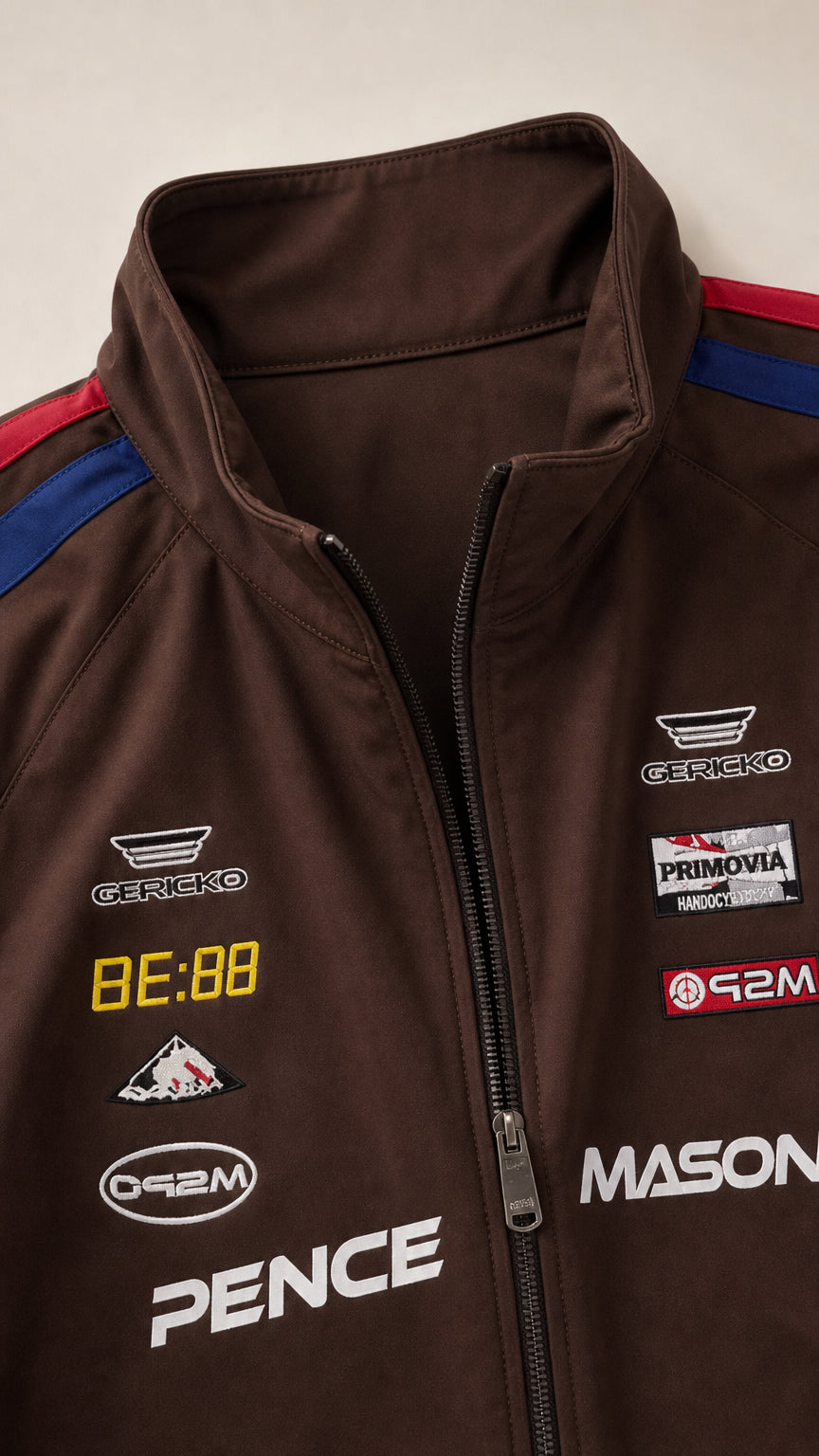 Close-up detail of collar, front zipper, and racing graphic prints on brown track jacket