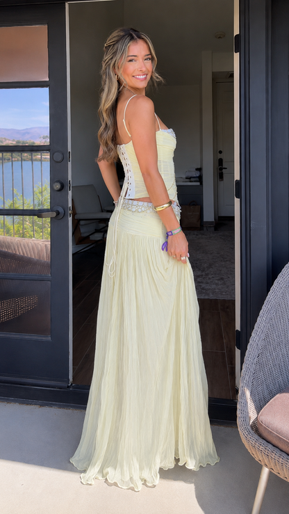 Side view of butter yellow sleeveless corset top and full pleated skirt set