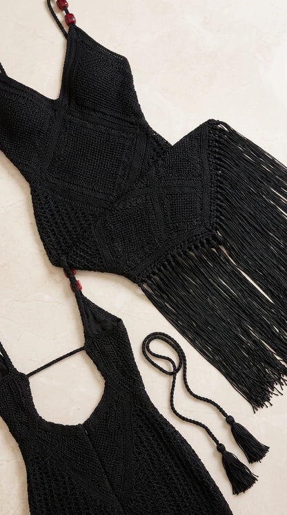 Close-up flat lay of black crochet knit pattern, beaded straps, and fringe trim