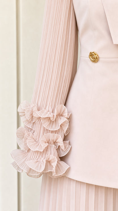 Close-up detail of pleated sleeve with tiered ruffles and gold flower button