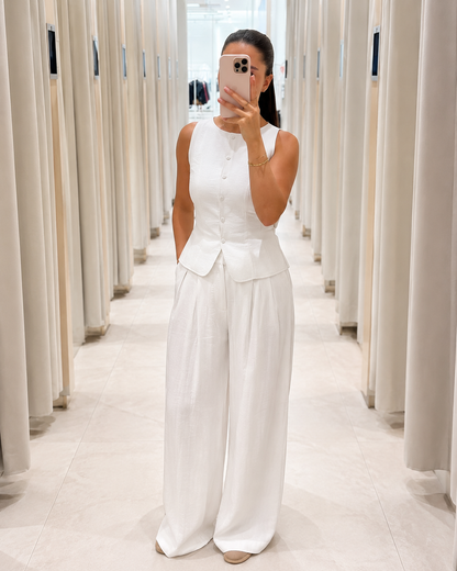 Front view of white sleeveless peplum top and wide leg pants matching set