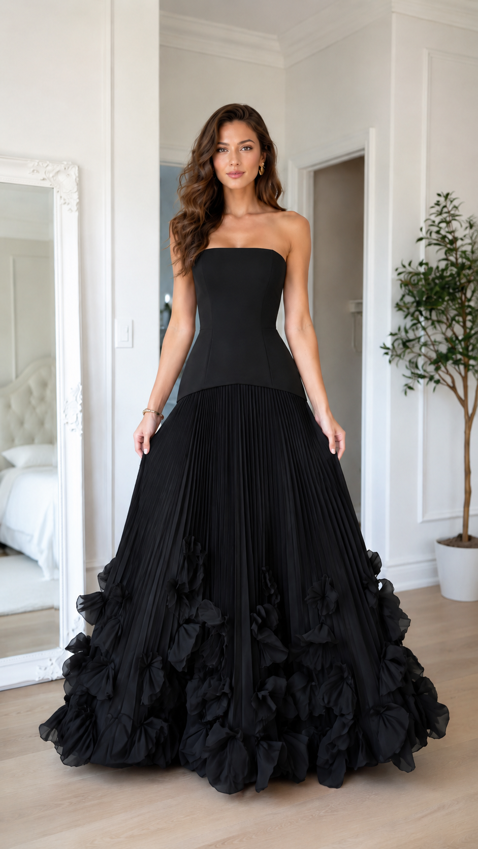 Front view of black strapless pleated maxi gown with statement ruffle hem