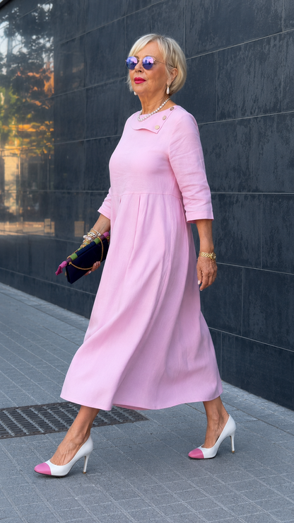 Side view of blush pink dress highlighting drape and button-trim fold-over neckline