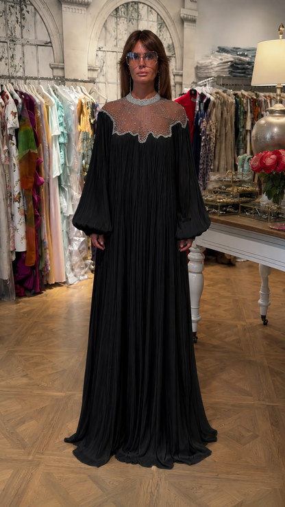 Front view of black pleated maxi dress with beaded sheer yoke and long sleeves
