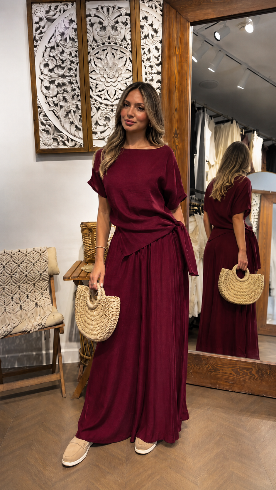 Woman wearing a burgundy draped waist maxi dress with short sleeves and side tie detail