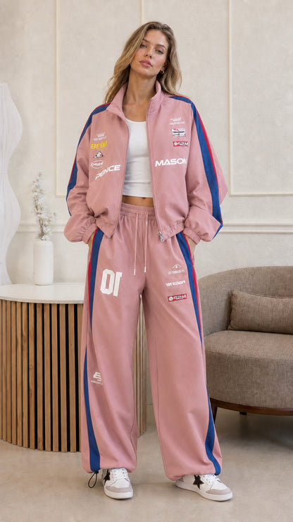 Full front view of woman wearing dusty pink graphic racing tracksuit set