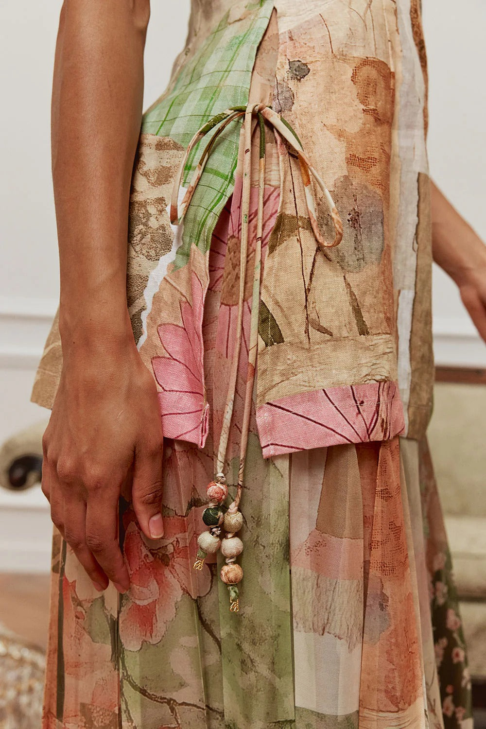 Close-up of the side tie detail with tassel-style ends on the patchwork print dress