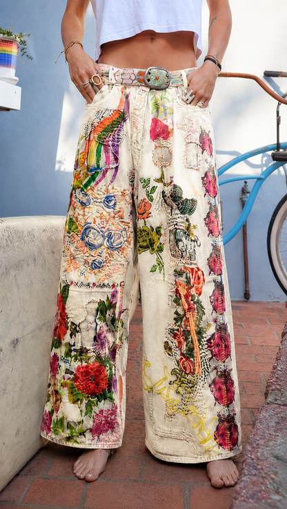 Front view of cream wide leg jeans with floral patchwork motifs and high-rise waist