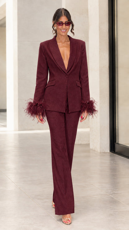 Front view of woman wearing burgundy tailored suit set with matching feather cuffs