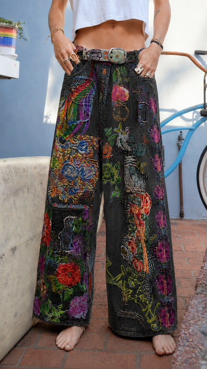 Front view of black wide leg jeans with colorful patchwork floral design and belt detail