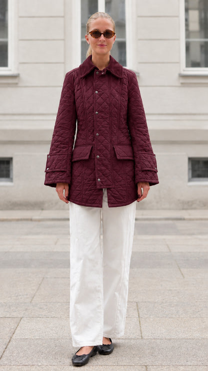 Front full-length view of woman wearing burgundy diamond quilted barn jacket
