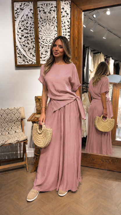 Woman wearing a dusty rose draped waist maxi dress with soft gathered movement