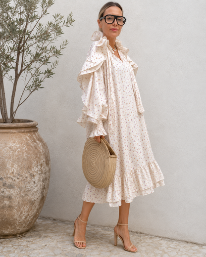 Three-quarter view of cream floral midi dress with woven bag styling