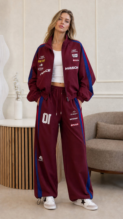 Full front view of woman wearing burgundy two-piece racing track suit