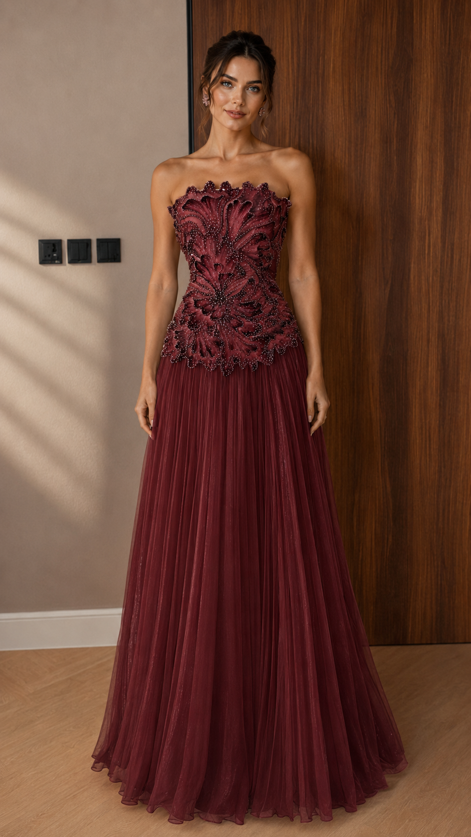 Front view of burgundy strapless appliqué formal dress with floor-length pleated skirt
