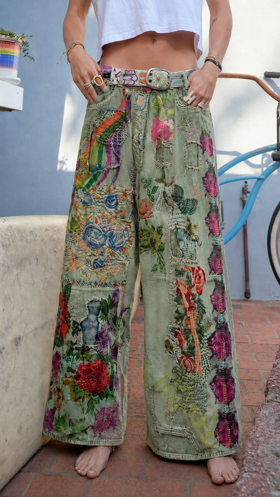 Front view of sage green wide leg jeans with floral patchwork and relaxed boho silhouette