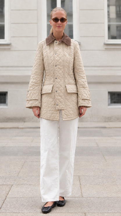 Front full-length view of woman wearing beige diamond quilted barn jacket
