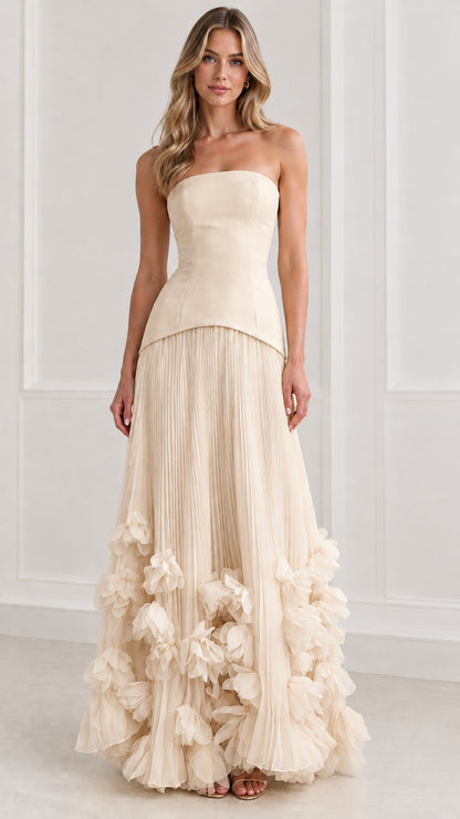 Front view of model wearing champagne cream strapless pleated maxi dress with 3D florals