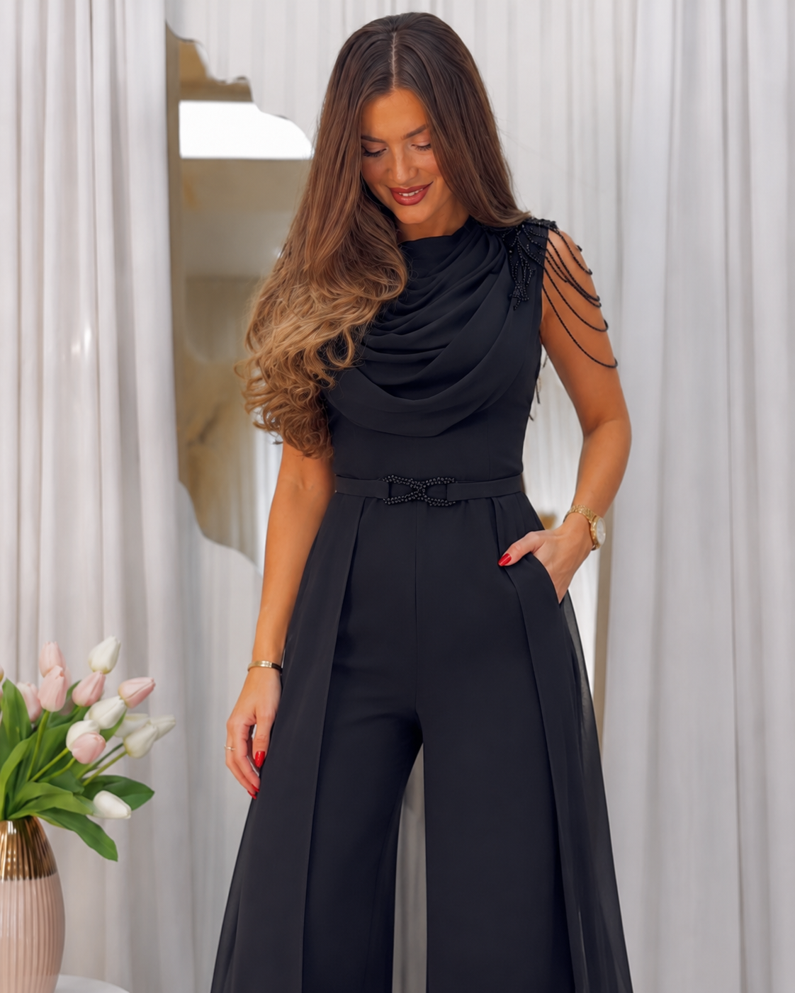 Close-up front view of draped neckline and waist detail on black jumpsuit